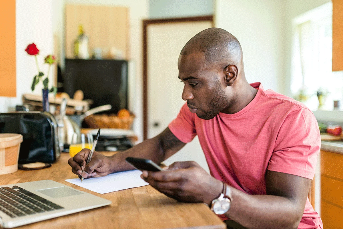 man writing whilst on phone